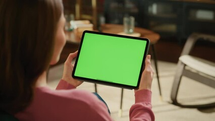 Leinwandbilder - Female Holding Tablet Computer with Green Screen Mock Up Display. Woman Relaxing at Home, Watching Videos and Reading Social Media Posts on Mobile Device. Close Up Over the Shoulder Footage.