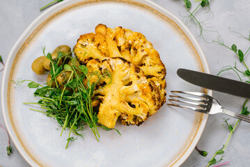 Grilled cauliflower dish with olives and microgreens. Vegan menu