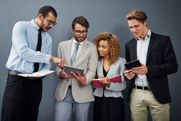 Wall Mural - Whats that. Cropped shot of a group of businesspeople using digital tablets and notebooks while waiting in line for a job interview.