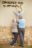 Fototapeta  - Old with an attitude. Shot of mischievous pensioners spray-painting graffiti on a wall.