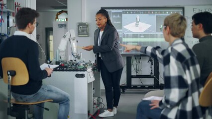 Aufkleber - Female Student Asking her Teacher while she Explaining Using Robot Arm at the Lesson. Diverse Group of Young Engineers Programming Robotic Hand. Computer Science Concept