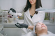 © Anna - Cosmetologist and dermatologist cleans the face of a lying woman patient in a beauty salon. Young woman on a cosmetology procedure for facial skin care