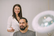 © Anna - Portrait of a young beautiful woman beautician in a medical white uniform and a young bearded man patient