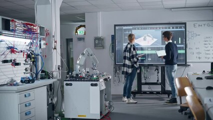 Leinwandbilder - Two Male and Female Students Standing Near Big Screen and Discussing Program for Motion of Robotic Arm while Studying at University. Education and Innovative Technologies Concept. Slow Motion