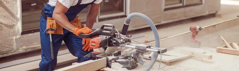 Male builder using wood cutting circular saw machine