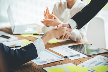 Glad to work with you! Fashionable young man in smart casual wear holding hands and smiling while working in a creative office.