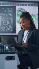 Aufkleber - Black Developer Typing at Laptop while Programming Robotic Arm at Laboratory. Woman Coding with Concentrated Face. Computer Language and Programming Concept. Vertical Video