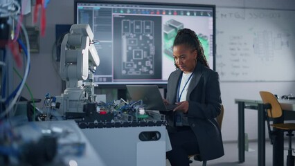 Leinwandbilder - Black Female Developer Controls Robot Hand with Laptop, while Writing Code at Computer Science Research Laboratory. High-Tech Science and Programming Concept