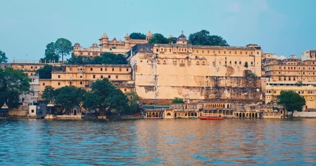 Fototapete - Udaipur City Palace view from lake Pichola on sunset with passing tourist boat. Jag Niwas is an example of Rajput architecture. Rajasthan is popular tourist Indian landmark. Incredible India heritage.