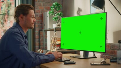 Poster - Young Handsome Man Working from Home on Desktop Computer with Green Screen Mock Up Display. Male Checking Corporate Accounts, Messaging Colleagues. Loft Living Room with Big Window. Handheld Shot.