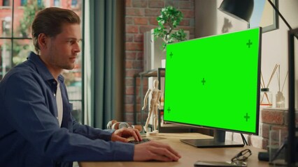 Poster - Young Handsome Man Working from Home on Desktop Computer with Green Screen Mock Up Display. Creative Male Checking Social Media, Browsing Internet. Living Room in Bright Loft Apartment. Static Shot.