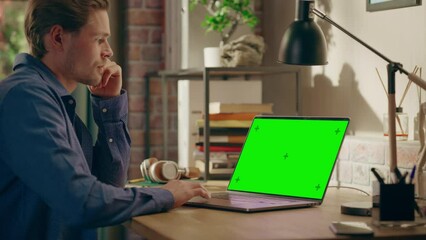 Aufkleber - Young Handsome Man Working from Home on Laptop Computer with Green Screen Mock Up Display. Creative Male Checking Social Media, Browsing Internet. Living Room in Loft City Apartment.