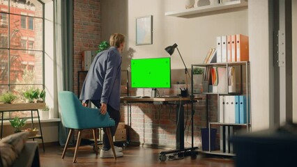 Poster - Young Handsome Man Sitting Down to Work from Home on Desktop Computer with Green Screen Mock Up Display. Creative Male Checking Social Media, Browsing Internet. Living Room in Bright Loft Apartment.