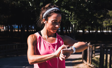 Young woman resting while looking at her results on a smartwatch after running. Healthy lifestyle. Selective focus.