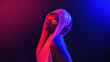 © Igor Link - Stylish fashion african teenager model wearing headphones listening dj music dancing in purple neon lights. Young teen girl enjoy cool music 90s party mix in violet studio background.