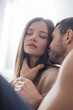 © LIGHTFIELD STUDIOS - Young man kissing and touching pretty girlfriend at home.