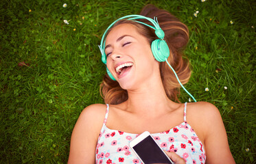 Canvas Print - This song just makes me so happy.... Shot of a young woman listening to music while lying on the grass.