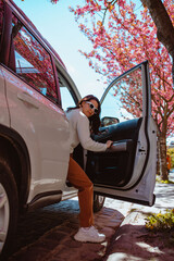 Wall Mural - woman get out of the car blooming sakura tree on background