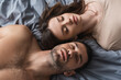 © LIGHTFIELD STUDIOS - Top view of brunette woman lying near shirtless boyfriend on bed.