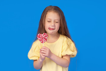 Wall Mural - Toothless child. Cute little girl smiles broadly with lollipop  in hands. The first milk tooth fell out. Carefree childhood concept and dental hygiene