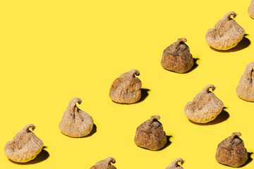 A pattern created of dried figs on bright optimistic yellow background. Creative copy space.