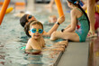 © Tomsickova - Child, taking swimming lessons in a group of children in indoor pool