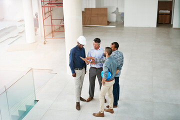 Poster - Planning for expansion. High angle shot of businessmen talking in the lobby of their office.