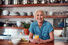 I Always Start My Day With A Glass Of Orange Juice. Cropped Portrait Of An Attractive Senior Woman Enjoying A Glass Of Orange Juice While Preparing Breakfast In The Kitchen.