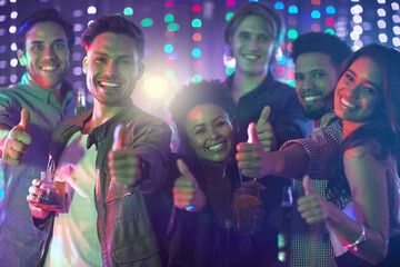 Poster - Friday night done right. Portrait of a happy group of friends giving a thumbs up while standing in a nightclub.