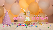 Beautiful Background Happy Birthday Number 42 With Burning Candles, Birthday Candles Pink Letters For Forty Two Years. Festive Background With Balloons