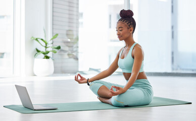 Poster - Learning the importance of yoga online. Full length shot of an attractive young woman sitting with her legs crossed and following an online yoga class.