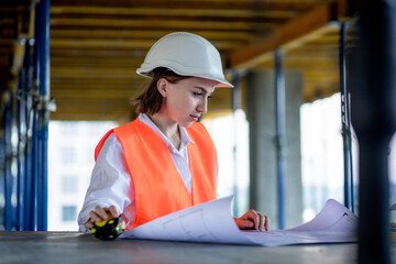 Architect or engineer working, browsing building project indoor of construction site with blueprint plan. Woman construction engineers or architects working people