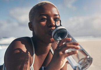 Wall Mural - A healthy lifestyle means staying fit and drinking enough water. Shot of a sporty young woman drinking water while out for a workout.