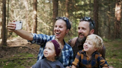 Wall Mural - family with small children having picnic in summer forest and taking selfie.