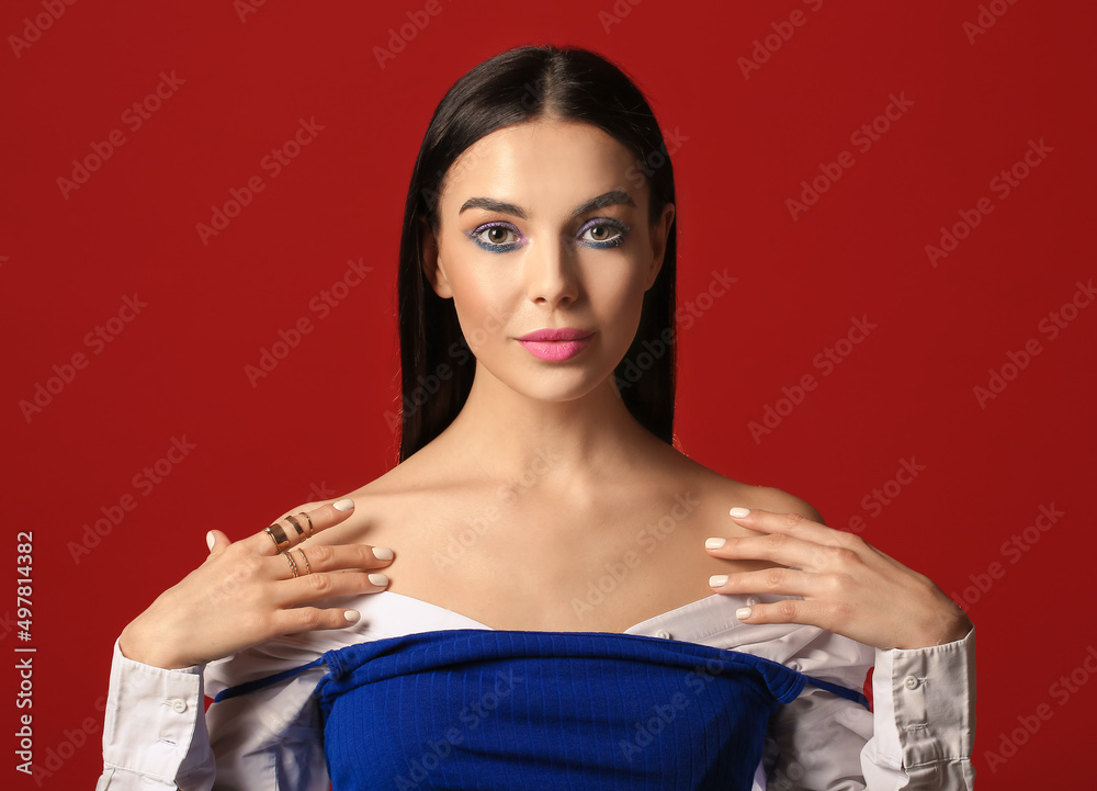 Beautiful young woman with creative makeup on red background