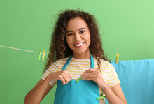 Young African-American Woman With Clothespins On Green Background