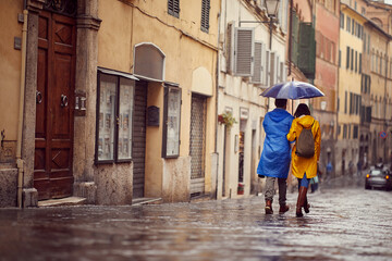 Wall Mural - Man and woman in raincoats are walking in the rain