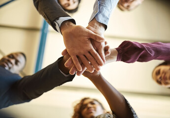 Aufkleber - Brought together by business. Low angle shot of a team of businesspeople piling their hands on top of each other in the office.
