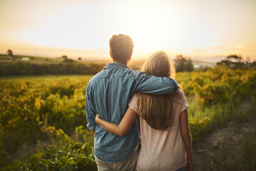 Look at what weve accomplished. Shot of a young couple walking through their crops while holding each other and looking into the horizon.