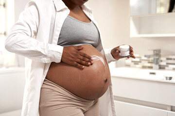 Wall Mural - Giving her baby bump some moisture. Closeup shot of a pregnant woman applying cream on her stomach at home.