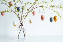 Vase With Spring Branches Of Blossoming Trees, Colorful Easter Eggs On A White Table