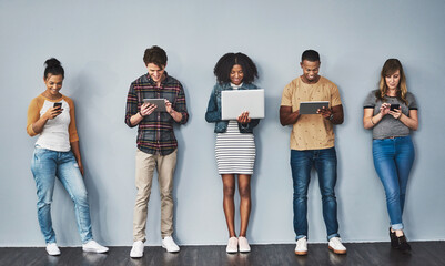 Aufkleber - Logged into modern life. Studio shot of a group of young people using wireless technology against a gray background.