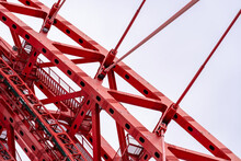 Close-up Of Fragment Of Red Cable-stayed Bridge Pylon In Place Where Metal Cables Are Fastened. Close-up Shows Connection Of Steel Powerful Straight Crossbar, Bridge Connection, Metal Architecture.