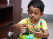 © Arindam - an indian baby boy engaged with a bead puzzle toy, developmental activity milestone concept image