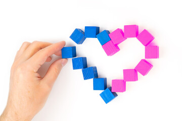 Building a heart symbol from wooden blocks on white