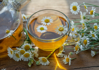 Wall Mural - Herbal chamomile tea and chamomile flowers on wooden table. Top view.