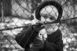 Little refugee girl with a toy behind a metal fence. Social problem of refugees and internally displaced persons. Russia's war against the Ukrainian people