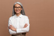 © Vadim Pastuh - Positive sanguine senior woman smiling cheerfully while posing arms crossed. Hilarious mature asian gray-haired lady standing isolated over beige background