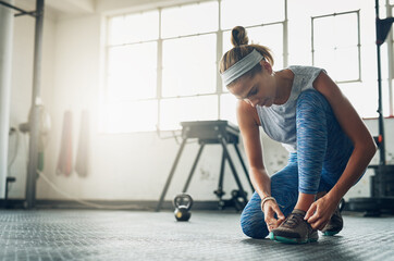 Poster - i dont want my shoes falling off during a workout. shot of a young attractive woman tying her shoela