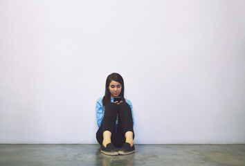 Fototapete - Shes between classes. Shot of an attractive young college student using her cellphone while sitting in a campus hallway.